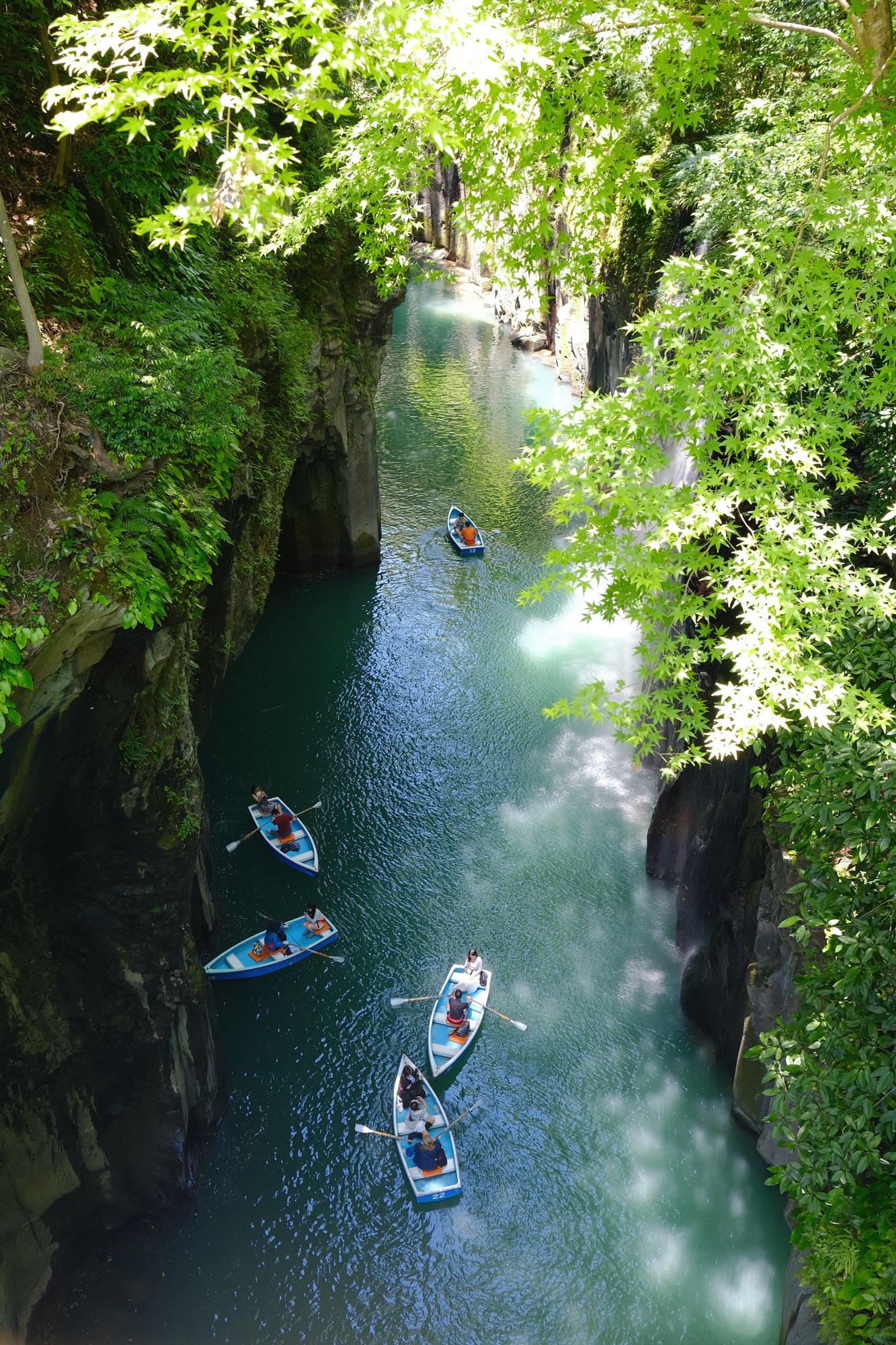 Rowboats on the emerald river through a lush green gorge, Takachiho Gorge, Japan, by Scott Yip